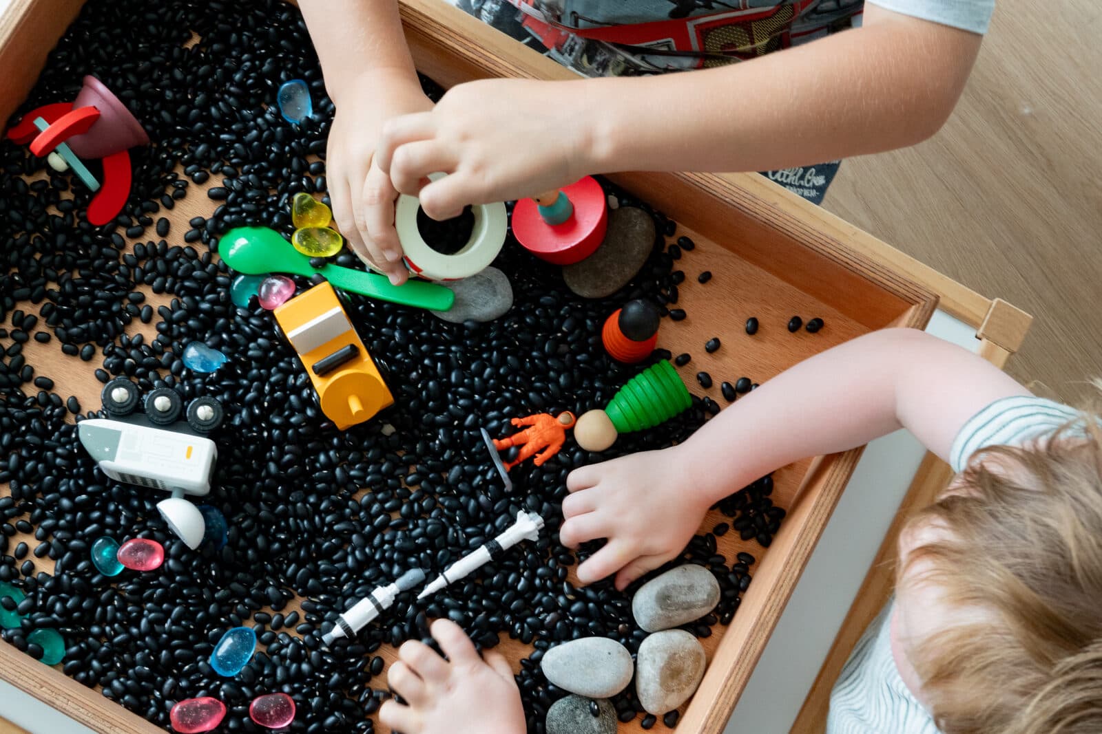 Kinderen ontdekken sensorische tray met zwarte bonen